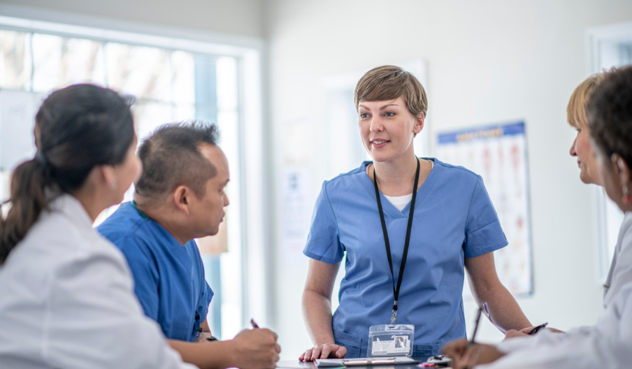 Smiling healthcare team collaborating respectfully during a shift huddle to improve patient care and teamwork. | CHCM