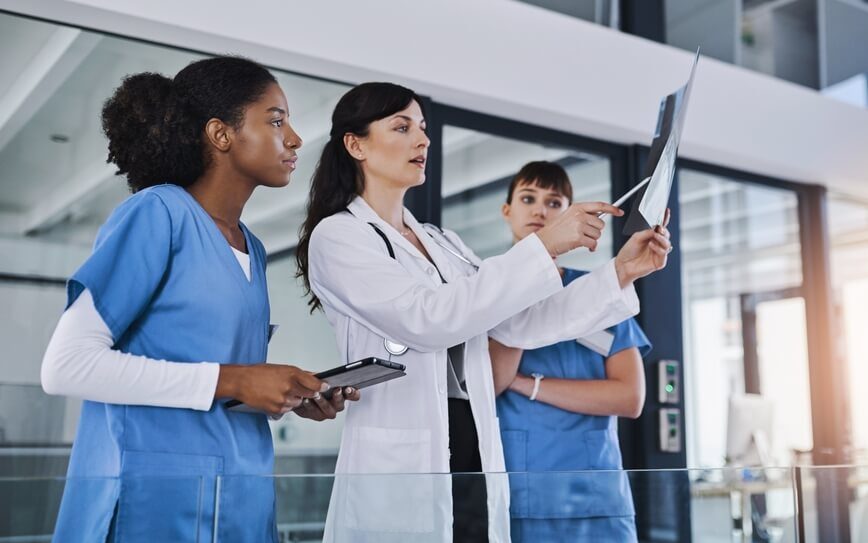 Three nurses look at an open folder