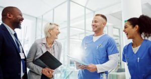 A team of four health care workers laugh together, demonstrating the essentails of a caring culture