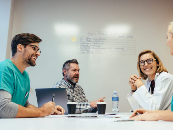 A group of doctors and nurses sit around a table, discussing and planning for the Magnet Recognition process.