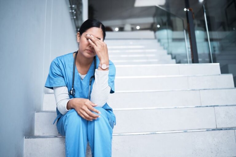 A moment of nursing burnout as a nurse sits on steps