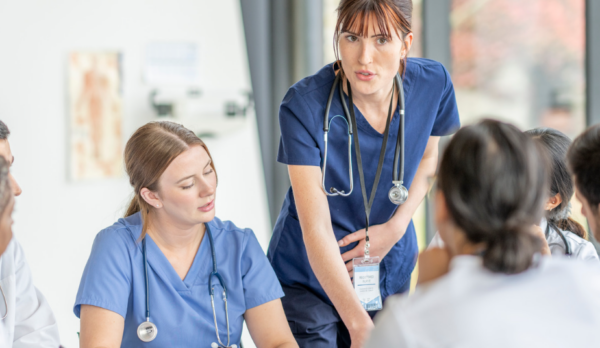 Nurse leading a professional practice discussion with healthcare team members