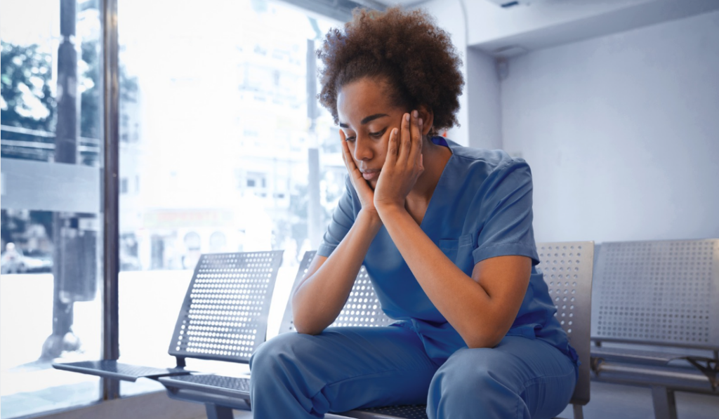 Nurse sitting at a nurses' station appearing emotionally exhausted after a hospital shift | CHCM
