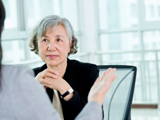 Female health care consulting partner sits with her hands folded in front of her