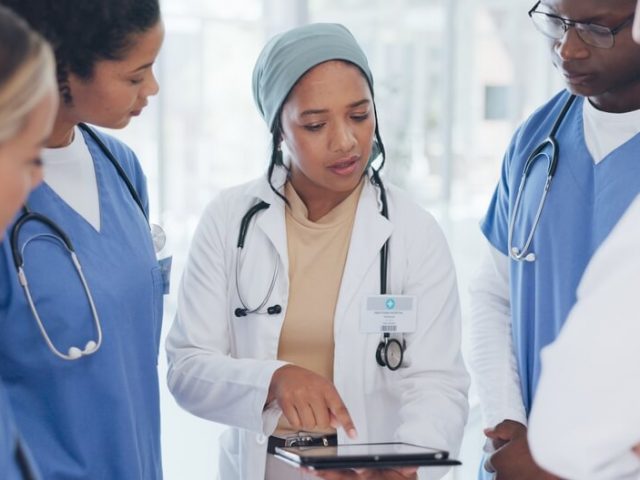 Nursing team gathers around looking at a tablet