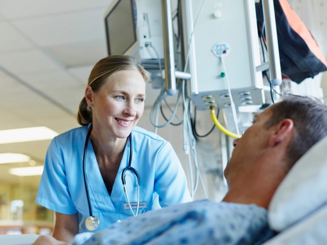 Nurse smiles down at a patient in bed