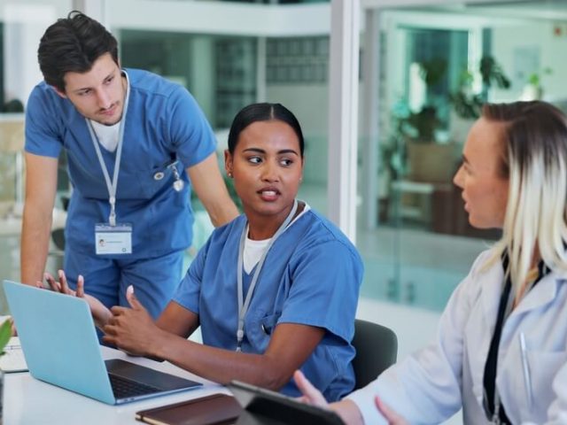 Team of nurses sit at a table, talking