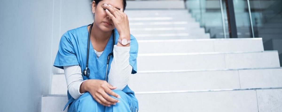 A moment of nursing burnout as a nurse sits on steps